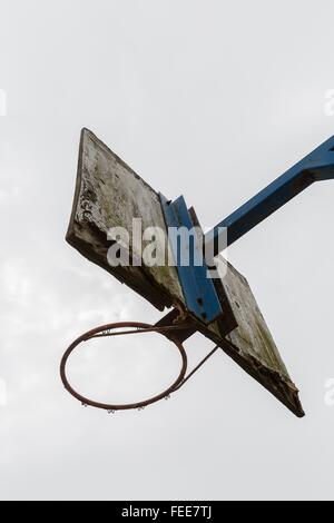 Un vecchio anello di pallacanestro con un bianco piatto in legno in cui la vernice che si staccava e fissata ad un blue steel pole su sfondo bianco Foto Stock