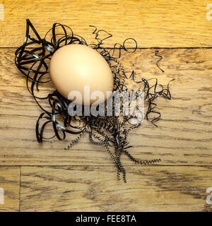 Uova su uno sfondo di legno nel nido di limature di ferro Foto Stock