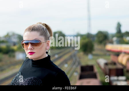 Ritratto di donna bella contro il treno e i binari ferroviari Foto Stock