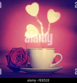 In stile vintage foto di una tazza di caffè con red rose fiori e cuori bianco decorazione su sfondo rosso, il giorno di San Valentino Foto Stock