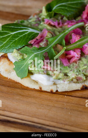 In prossimità di una fetta biscottata di pane piatto condito con una casa fatta diffondere utilizzando avocado e cavolo fermentato e poi rabboccato wit Foto Stock