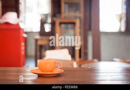 Orange tazza di caffè sul tavolo di legno nel coffee shop Foto Stock