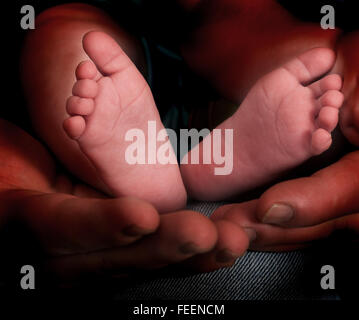 Padre tiene nelle sue mani un piccolo piedi del bambino Foto Stock