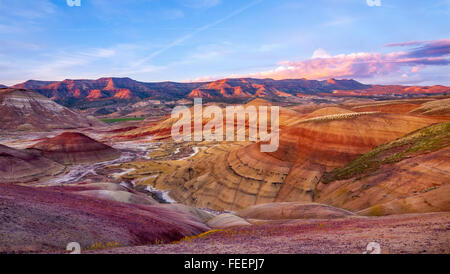 Gli ultimi raggi del sole al tramonto luce le scogliere lontano dietro le colline dipinte. Oregon, Stati Uniti d'America. Foto Stock