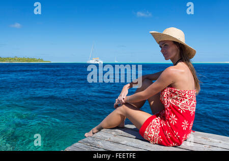 Donna seduta sul molo, Tetamanu, Fakarava, isole Tuamotu, Polinesia Francese Foto Stock