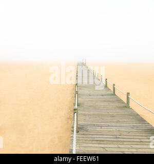 Passerella in legno su un foggy spiaggia di sabbia. Figueira da Foz, del Portogallo, dell'Europa. Foto Stock