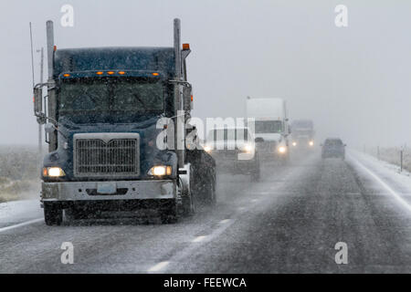 Pomeriggio nevoso su una trafficata autostrada con il traffico e la scarsa visibilità per un inverno di concetto di attenzione Foto Stock