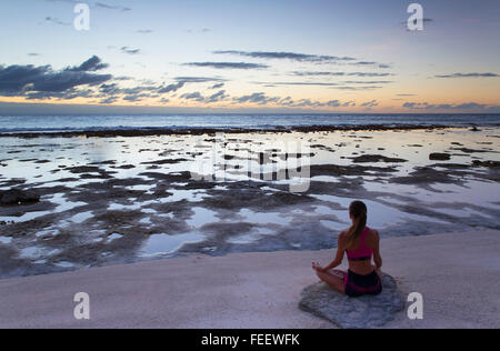 La donna a praticare yoga sulla spiaggia al tramonto, Fakarava, isole Tuamotu, Polinesia Francese Foto Stock