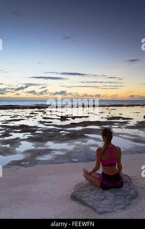 La donna a praticare yoga sulla spiaggia al tramonto, Fakarava, isole Tuamotu, Polinesia Francese Foto Stock