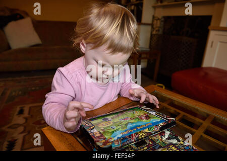 Un diciotto mesi concentrando toddler durante la riproduzione di un gioco su un ipad nella sua casa. Foto Stock