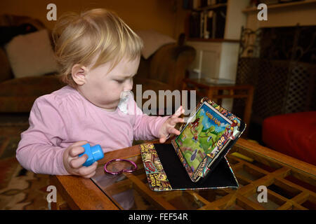 Un diciotto mesi concentrando toddler durante la riproduzione di un gioco su un ipad nella sua casa. Foto Stock