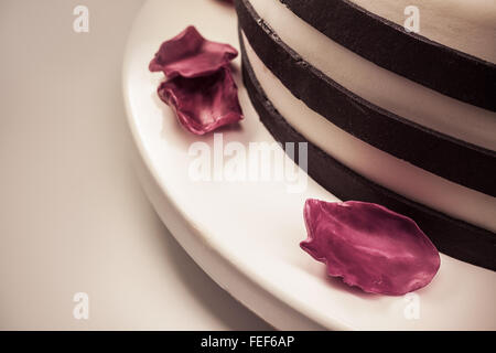 Dettagli di una torta, caduti petali viola fatta di zucchero come decorazione. Foto Stock