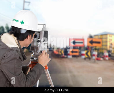 I tecnici utilizzano tacheometer o teodolite con costruzione di opere stradali sullo sfondo Foto Stock