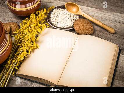 Farina di avena cookie e un vecchio libro di ricette sul tavolo della cucina Foto Stock
