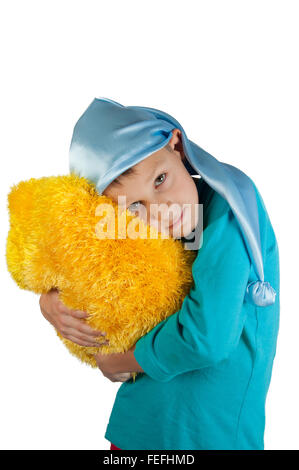 Ragazzo pigiami blu e dormire hat holding cuscino giallo isolato su bianco Foto Stock