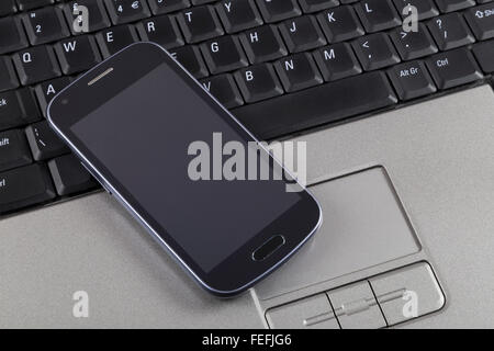 Telefono cellulare sulla tastiera del notebook Foto Stock