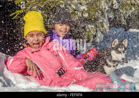 Due bambine che giocano sulla neve con cani Husky Foto Stock