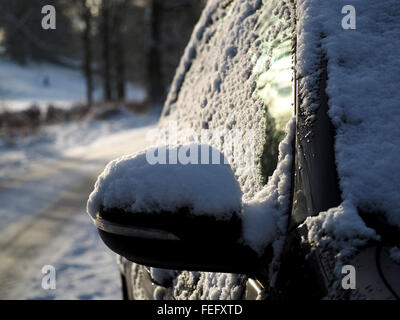 Auto specchietto laterale e windows con una copertura di neve in inverno una brutta nord strada rurale Foto Stock