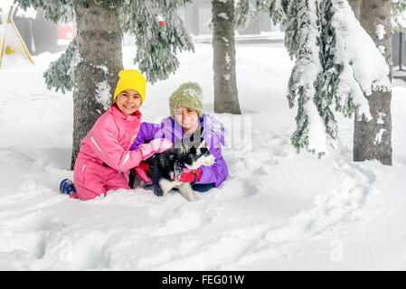 Bambine giocando con cani Husky sulla neve Foto Stock