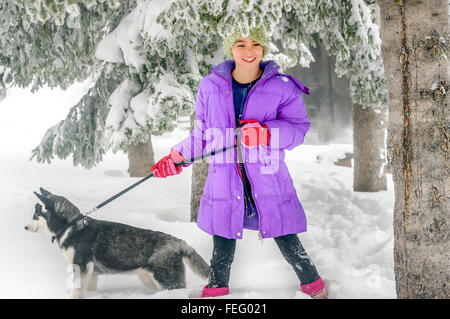 Bambina gioca con cani Husky sulla neve Foto Stock