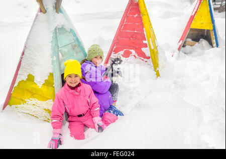 Bambine giocando con cani Husky sulla neve Foto Stock