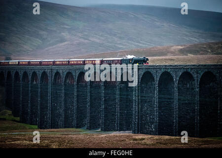 Ribblehead, vicino a Settle, North Yorkshire. Sabato 6 Febbraio 2016. Una delle più famose al mondo per le locomotive, il Flying Scotsman, ha restituito alla West Coast mainline a seguito di una £4.2m, 10 anni di progetto di restauro. Viaggiando da Carnforth sulla linea principale della costa occidentale di Carlisle e poi ritornare attraverso la storica Settle Carlisle dalla stazione ferroviaria, il treno è raffigurato attraversando il viadotto Ribblehead al crepuscolo. Il motore è stato ritirato dal servizio nel 1963 ed è stato restaurato per il York National Railway Museum di Riley e Son Ltd, basato a Bury. Credito: Ian Wray/Alamy Live News Foto Stock