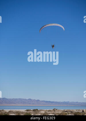 Un uomo vola nel suo paramotore ultralight in aria da Salton Sea, California. Powered parapendio o paramotoring. Foto Stock