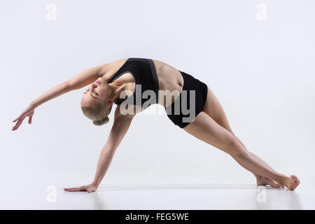 Sporty bella giovane donna a praticare yoga, facendo la variazione della posizione del cobra postura, posa di Vashista, Vasisthasana con la piegatura Foto Stock