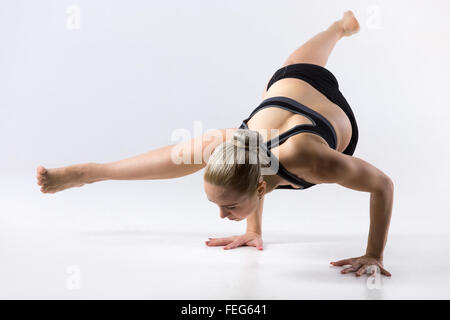 Sporty bella giovane donna a praticare yoga, facendo Eka Pada Koundinyasana 1, pongono dedicata alla salvia Koundinya ho Foto Stock