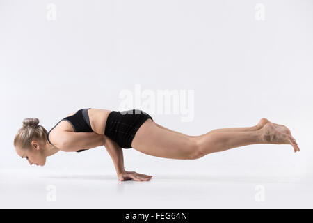 Sporty bella giovane donna a praticare yoga, facendo handstand Peacock pongono, Mayurasana, la tonificazione dei muscoli addominali, gli avambracci Foto Stock