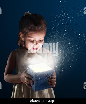 Bambina apre un dono. Esso è illuminato dall'interno. Dark - sfondo blu. Foto Stock