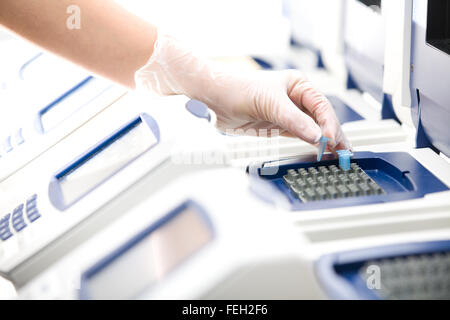 Scienziato, copia del DNA, la PCR in tempo reale cycler, guanti bianchi, distante Foto Stock