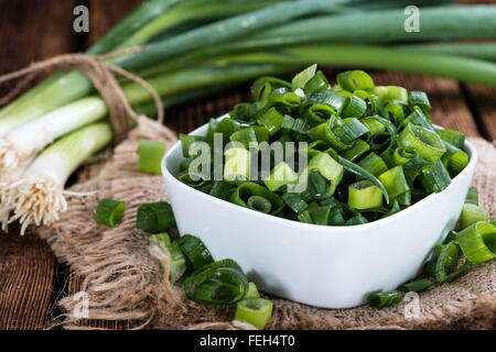 Lo scalogno (fresco tagliato) come close-up shot su sfondo di legno Foto Stock