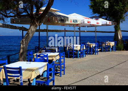 Creta, Rethymnon, street restaurant con sguardo sul mare blu, sedie, tavoli e ombrelloni Foto Stock