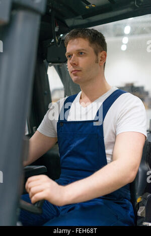 Operatore carrello elevatore a forche lavora in magazzino. Foto Stock