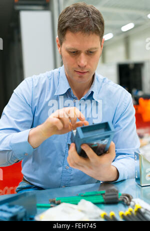 Bello lavoratore assemblaggio di componenti elettronici in fabbrica. Foto Stock