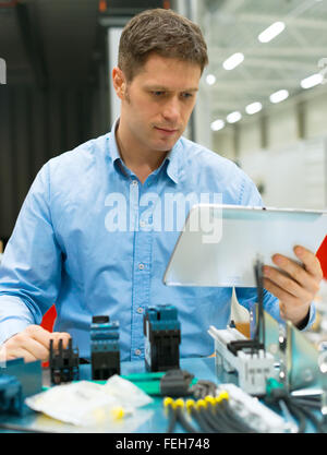Bello lavoratore assemblaggio di componenti elettronici in fabbrica. Foto Stock