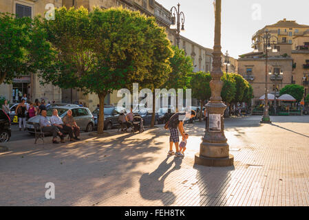 Padre bambino Italia, alla fine di un giorno di estate in Piazza Vittorio Emanuele di Enna, Sicilia, un giovane padre aiuta il suo bambino figlio di camminare. Foto Stock