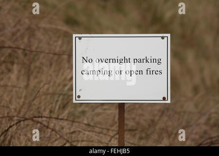 Un No parcheggio notturno, Camping o fuochi aperti segno a nord Sunderland nel Northumberland, Inghilterra. Il segno è sulle dune. Foto Stock