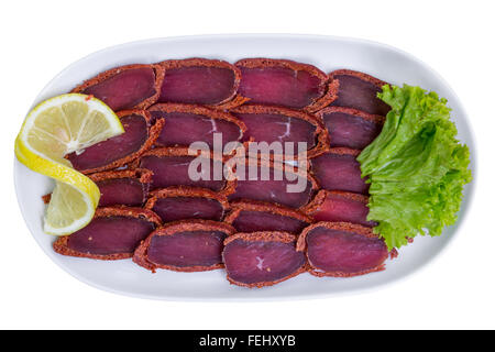 Basturma, maiale carne essiccata con il limone sulla piastra bianca, vista dall'alto, isolato Foto Stock