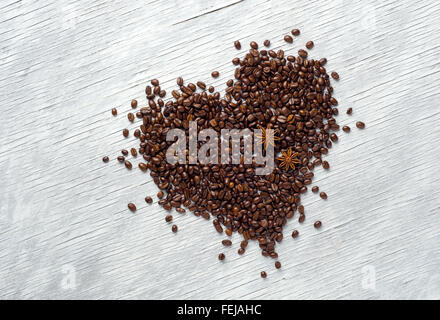 Forma di cuore fatta da chicchi di caffè su sfondo di legno Foto Stock