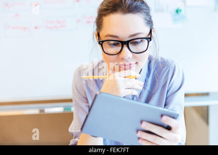 Giovane imprenditrice lavora con Tablet PC in ufficio Foto Stock