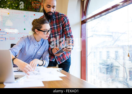 Due giovani donna e uomo designer di moda e di lavoro utilizzando tablet insieme Foto Stock