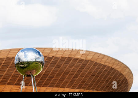 Una sfera riflettente di scultura con il velodromo in background, Olympic Park, Stratford, London, E15. Foto Stock