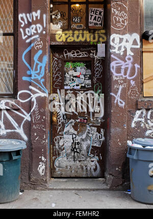 Ingresso di un edificio fatiscente su East Fourth Street nel Greenwich Village con cestini della spazzatura e graffiti. La città di New York Foto Stock