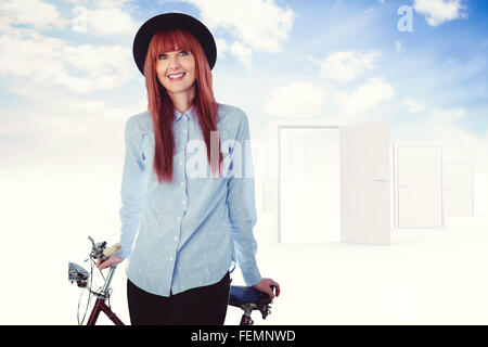 Immagine composita di sorridere hipster donna appoggiato su di una bicicletta Foto Stock