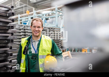 Ritratto lavoratore sorridente in indumenti da lavoro protettiva nella fabbrica di acciaio Foto Stock