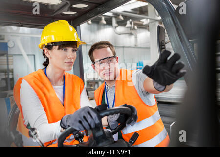 Lavoratore collega guida la guida carrello in fabbrica Foto Stock