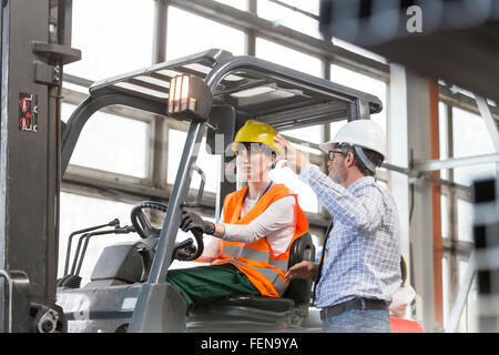 Supervisor dirigere il lavoratore la guida carrello in fabbrica Foto Stock