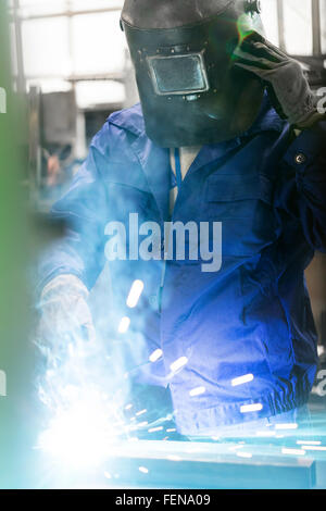 Saldatore in indumenti da lavoro protettiva a lavorare in fabbrica Foto Stock